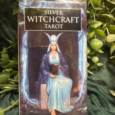 Caixa de baralho de tarot com figura feminina vestida de azul sentada, título SILVER WITCHCRAFT TAROT