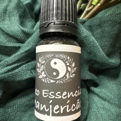Frasco pequeno de óleo essencial de manjericão com tampa preta e rótulo cinzento sobre tecido verde