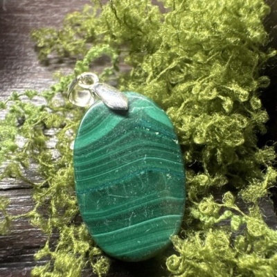 Pendente oval verde com suporte prateado sobre musgo verde
