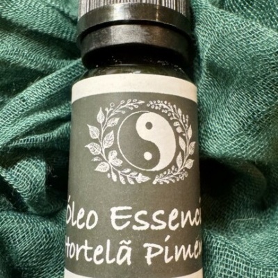 Frasco pequeno de óleo essencial Hortelã Pimenta com tampa preta sobre tecido verde