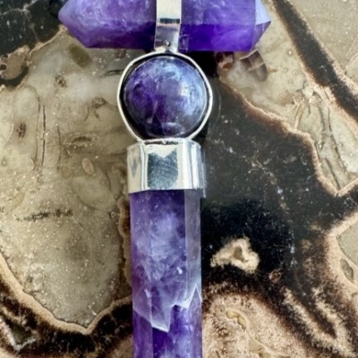 Colar com pendente em cristal violeta sobre pedra com padrões naturais