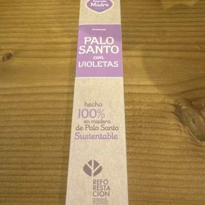 Embalagem de incenso Palo Santo com violetas em embalagem de papel reciclado sobre mesa de madeira clara