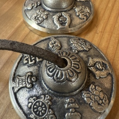 Par de címbalos tibetanos metálicos decorados com cordão sobre superfície de madeira
