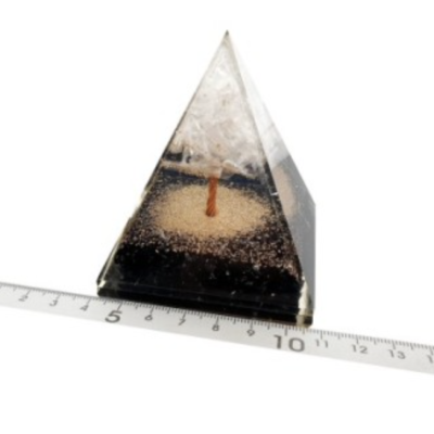 Pirâmide transparente decorativa com camadas internas coloridas e fio castanho central, sobre superfície branca com régua