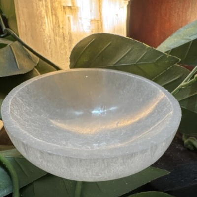Taça de pedra branca translúcida com folhas verdes ao fundo