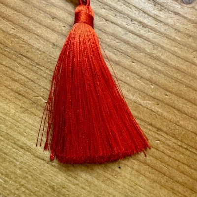 Pêndulo vermelho de fios finos sobre madeira clara