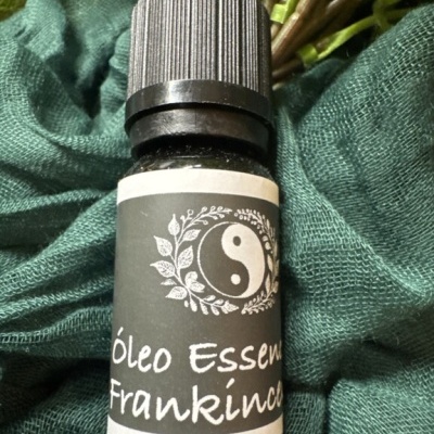 Frasco de óleo essencial Frankincense com tampa preta sobre tecido verde.