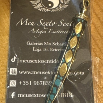 Pingente esotérico dourado e azul com cartão informativo preto