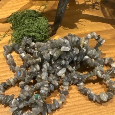 Pulseiras de pedras cinzentas sobre madeira com musgo e objeto de metal