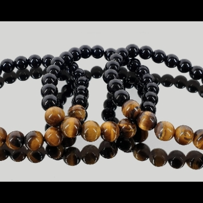 Pulseiras de contas pretas e castanhas com padrão em espiral sobre fundo cinzento