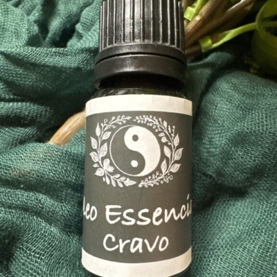 Frasco pequeno de óleo essencial com rótulo yin-yang e texto Cravo sobre tecido verde