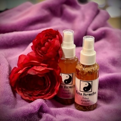 Dois frascos de spray com rótulos rosa vermelha e flores vermelhas sobre tecido roxo