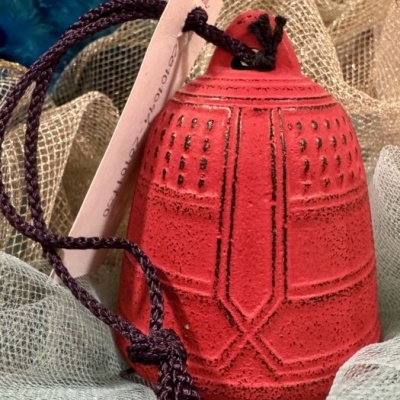 Sino vermelho decorativo com cordão roxo sobre tecidos translúcidos