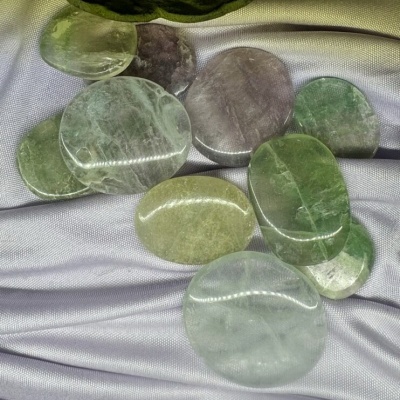 Pedras minerais polidas verdes e cinza sobre tecido cinzento prateado