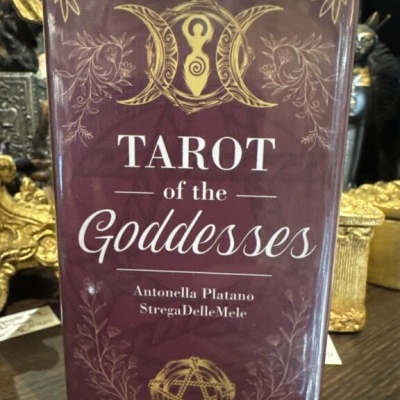 Caixa do baralho de tarot TAROT of the Goddesses com texto e símbolos dourados sobre fundo roxo.