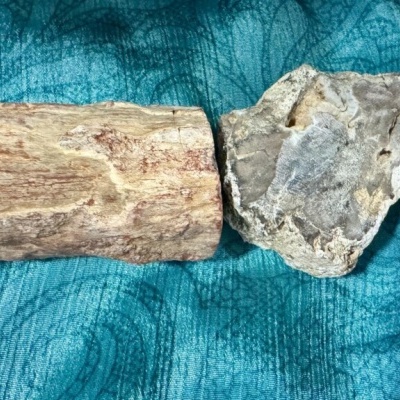 Dois objetos rústicos sobre tecido azul, um bloco de madeira e uma pedra cinzenta irregular
