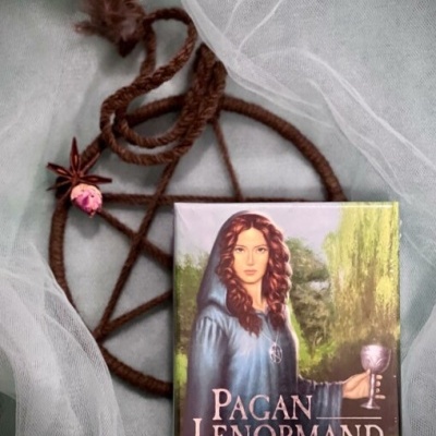 Caixa de cartas oraculares Pagan Lenormand junto a pentagrama trançado com corda e penas