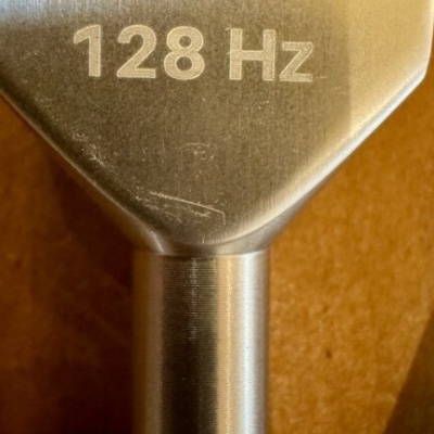 Diapasão metálico cinza com texto 128 Hz