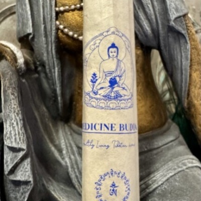 Incenso Medicine Buddha em embalagem de papel com figura de Buda azul sobre estátua de pedra