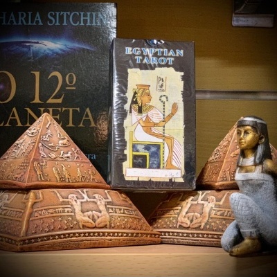Pirâmides decorativas, baralho Egyptian Tarot e estátua feminina egípcia sobre prateleira
