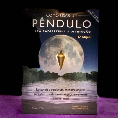 Capa de livro com pêndulo dourado, lua cheia e texto em português