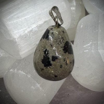 Pingente de pedra com padrão cinza e manchas negras sobre cristais brancos