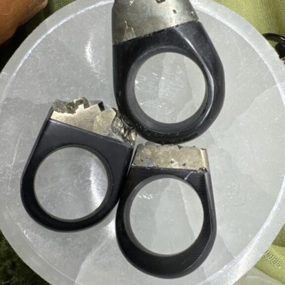 Três anéis pretos com topo prateado sobre prato branco