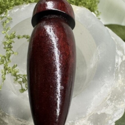 Objeto de madeira polida castanho escuro sobre suporte de cristal branco