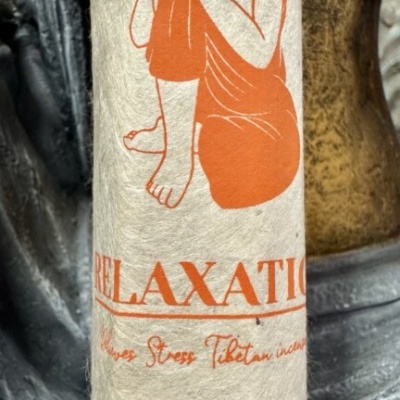 Pacote de incenso com figura meditativa e texto em laranja sobre papel bege texturizado
