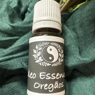 Frasco de óleo essencial de Orégãos sobre tecido verde
