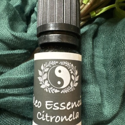 Frasco de óleo essencial de citronela com etiqueta preta e branca sobre tecido verde