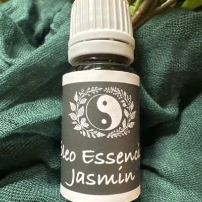 Frasco de vidro pequeno de óleo essencial de jasmim com rótulo preto e tampa branca sobre tecido verde.