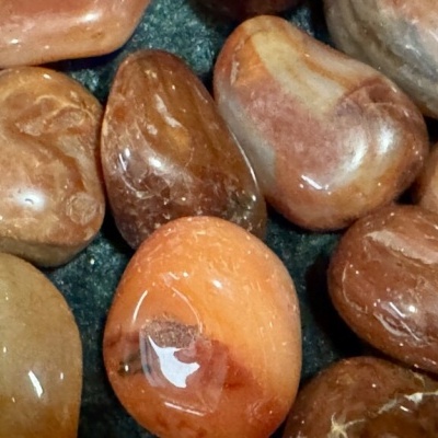 Pedras polidas castanhas e laranja sobre superfície escura