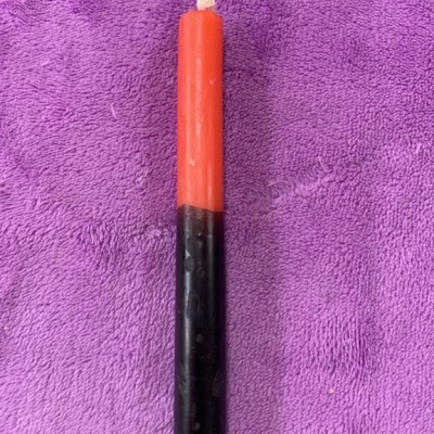 Vela vermelha e preta sobre tecido roxo