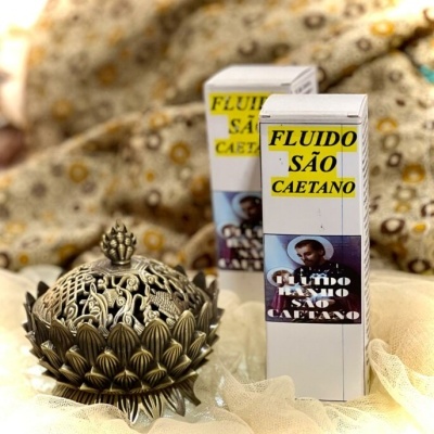 Produto FLUIDO SÃO CAETANO e objeto decorativo dourado sobre tecido bege