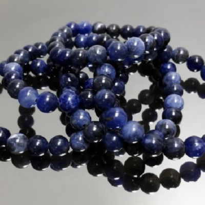 Pulseiras de contas de pedra azul sobre superfície espelhada