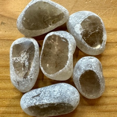 Seis pedras polidas transparentes com base cinzenta esbranquiçada sobre madeira