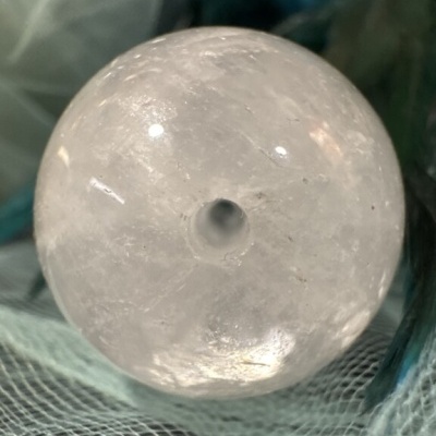 Esfera transparente de cristal com cavidade central sobre tecido azul e branco