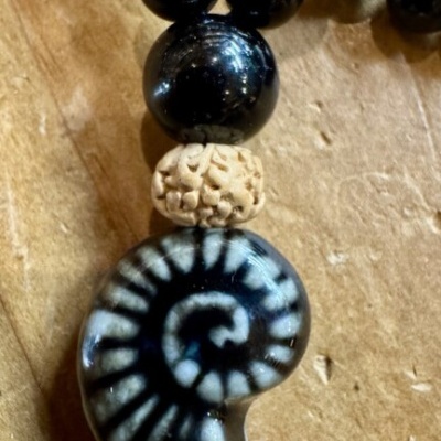 Colar com contas negras e pendente em forma de concha espiral