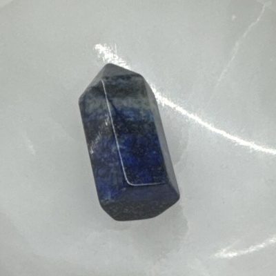 Cristal azul polido com acabamento facetado num prato branco