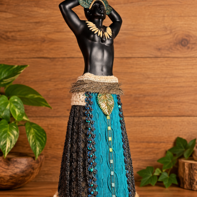 Estatueta decorativa masculina com adereços coloridos e saia de tecido sobre fundo de madeira.