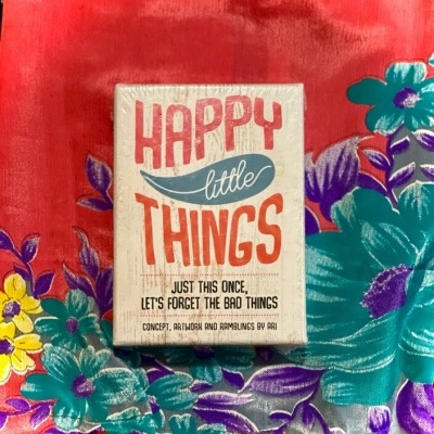 Caixa com texto Happy little Things sobre tecido floral vermelho