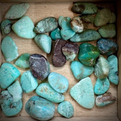 Pedras polidas de várias cores numa caixa de madeira
