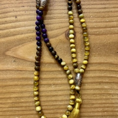 Colar de contas coloridas com tassel amarelo sobre mesa de madeira