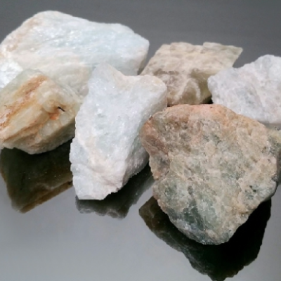 Seis pedras brancas e bege com texturas rugosas em superfície escura