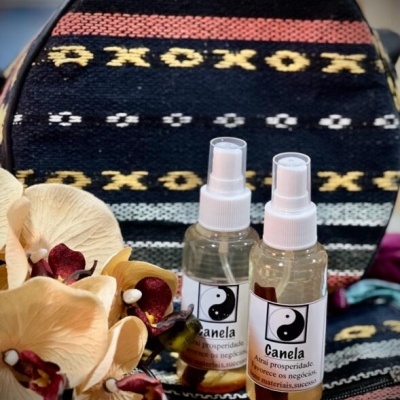 Dois frascos de spray Canela com etiqueta yin-yang sobre tecido colorido e flores artificiais