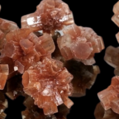 Cristais naturais de aragonite castanho e laranja em formas hexagonais sobre fundo preto