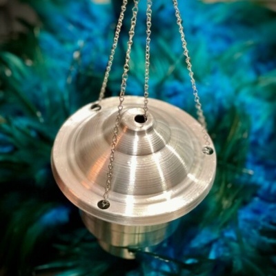 Incensário metálico prateado suspenso com correntes sobre penas azuis