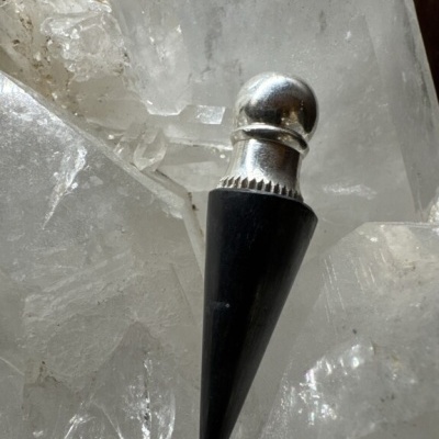 Pêndulo preto e prateado sobre cristais translúcidos