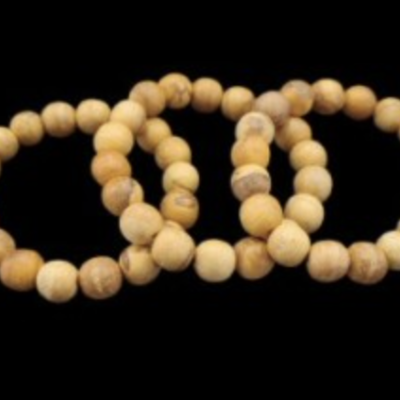 Três pulseiras de contas de madeira clara sobre fundo preto